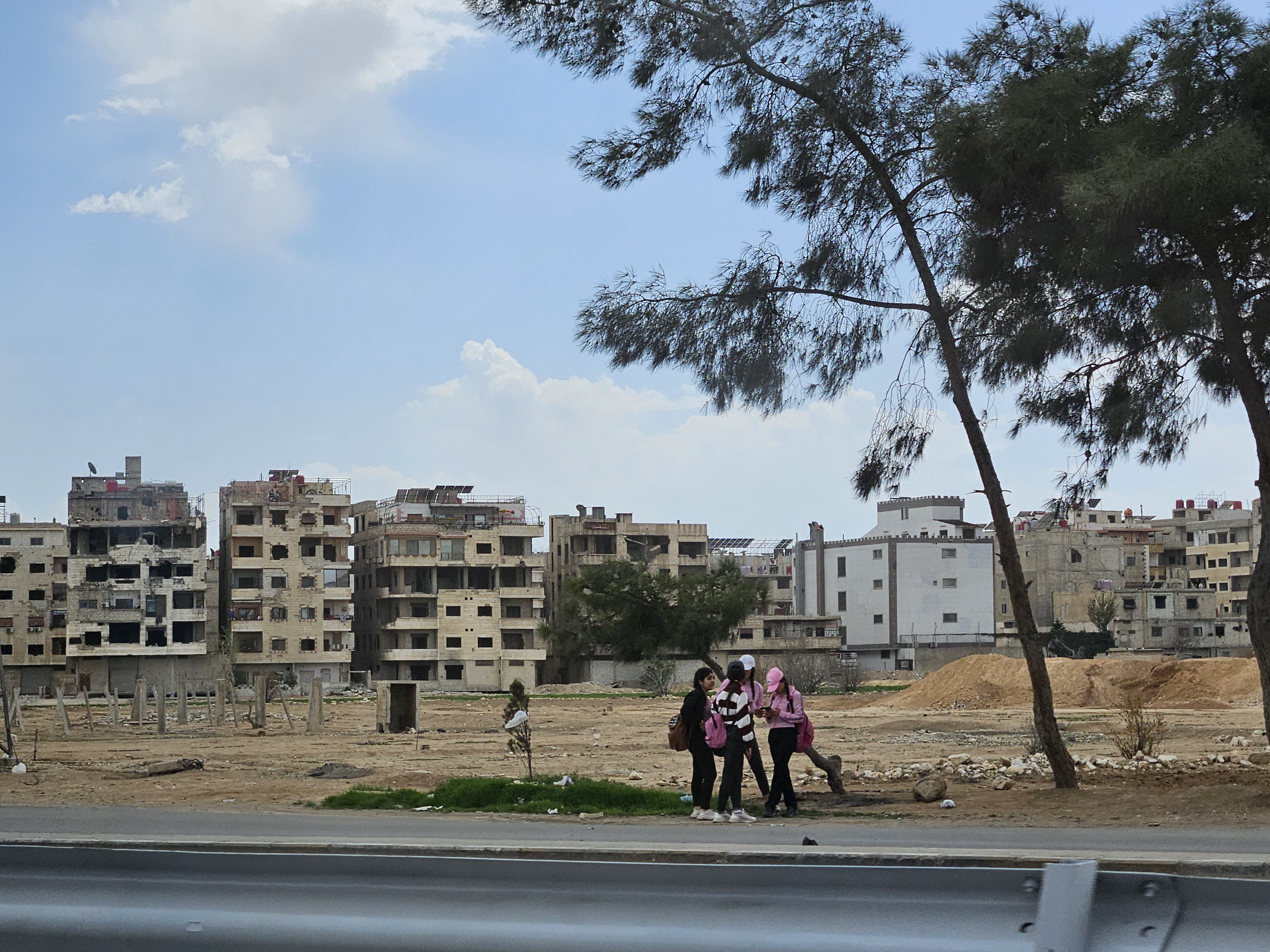 damaged houses in Damascus with people in front 