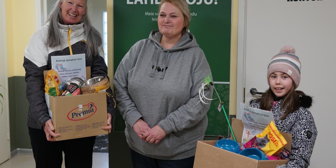 Three people standing infront of a wall with cardboard boxes