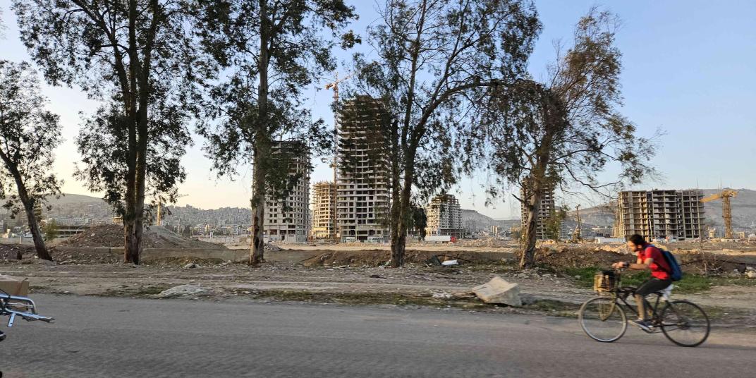 Man on a bicycle on the road in Syria, trees on the background