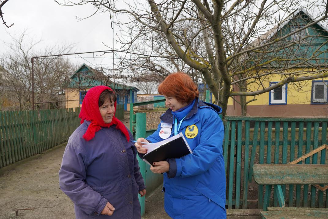 A staff member of Shchedryk Charitable Foundation speaks with Hanna Oleksandrivna. Kherson oblast, Novopavlivka village. December 9, 2025. Photo: Dana Selezen, ERC.