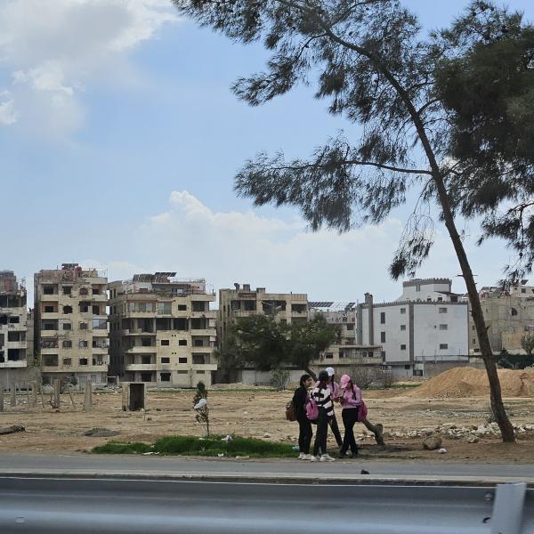 Landscape with destroyed houses and group of young people standing infant